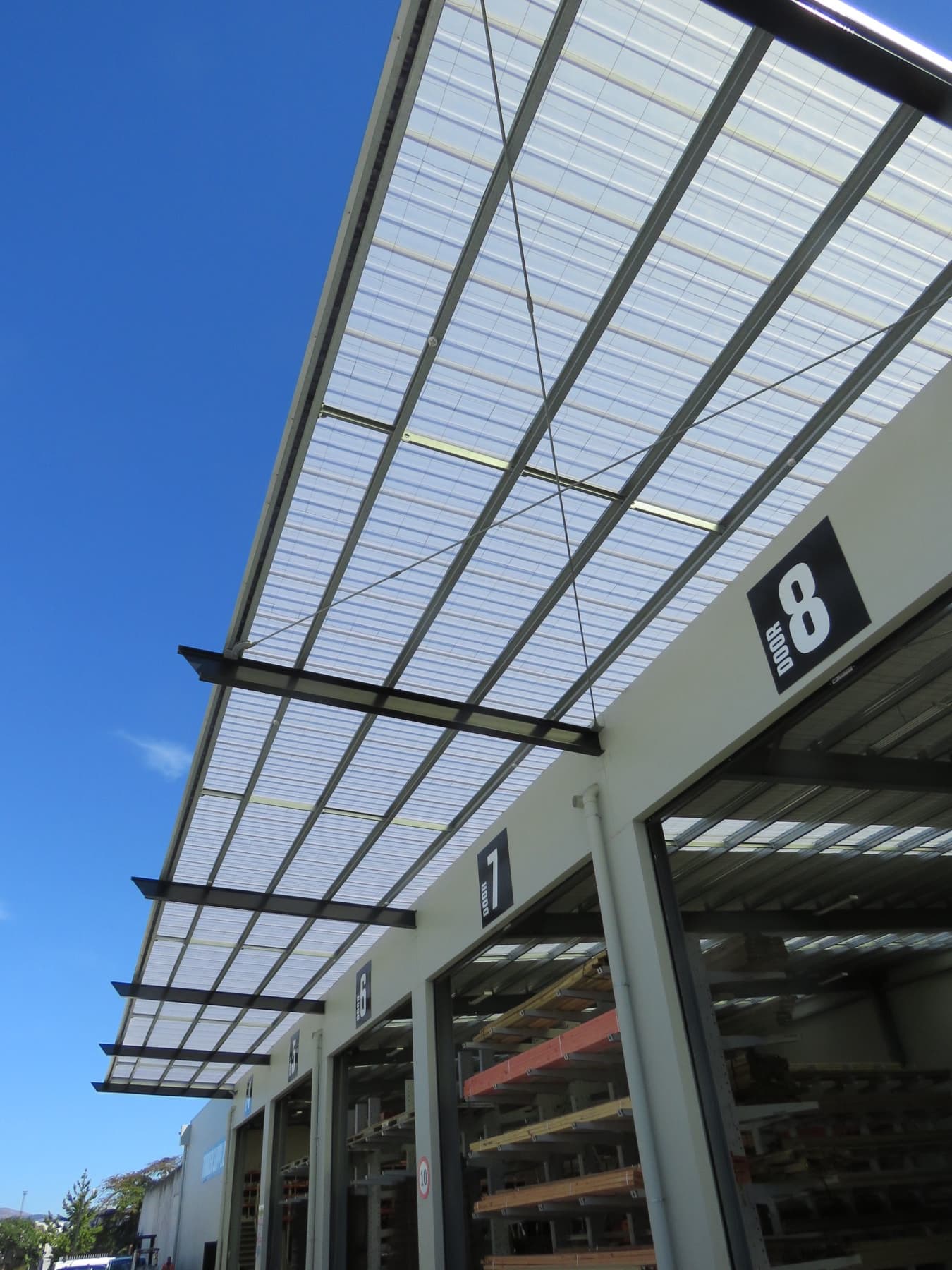 The trade drive-through: a translucent canopy over numbered bays, with racked timber behind.