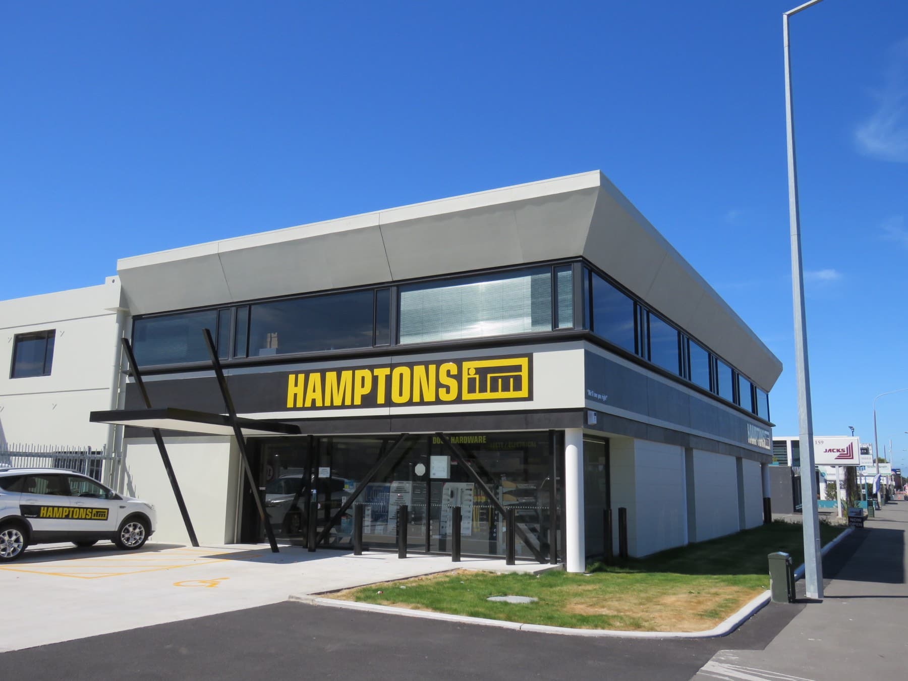 The completed two-storey building from the street, signage across the frontage and a Now Open sign at the kerb.