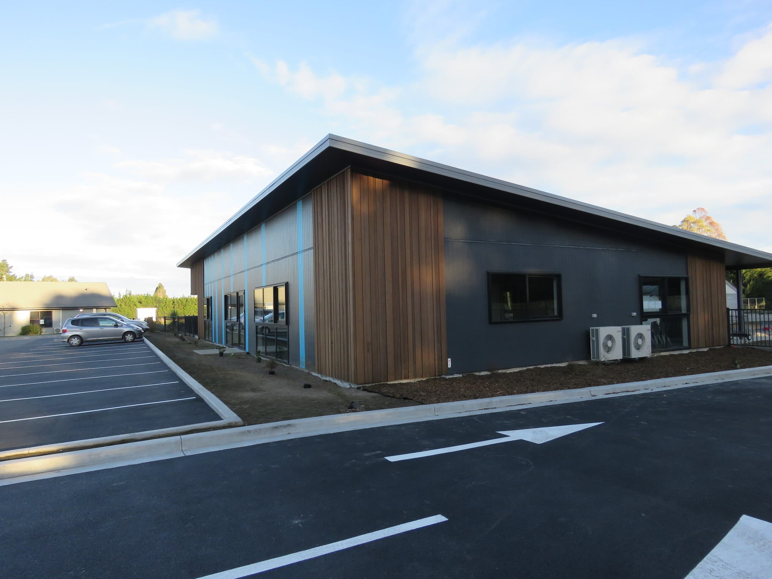 The completed teaching block from the carpark, cedar and dark cladding under a monopitch roof.