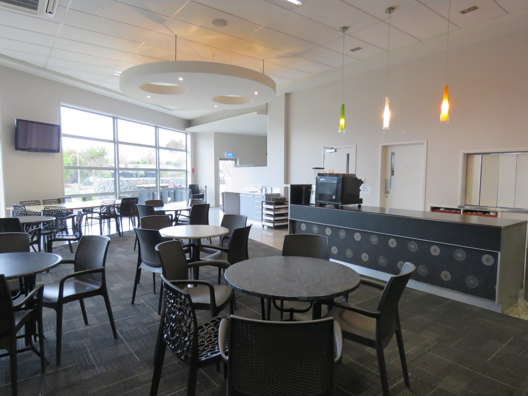 The cafe and servery, with loose tables and a counter along one wall.